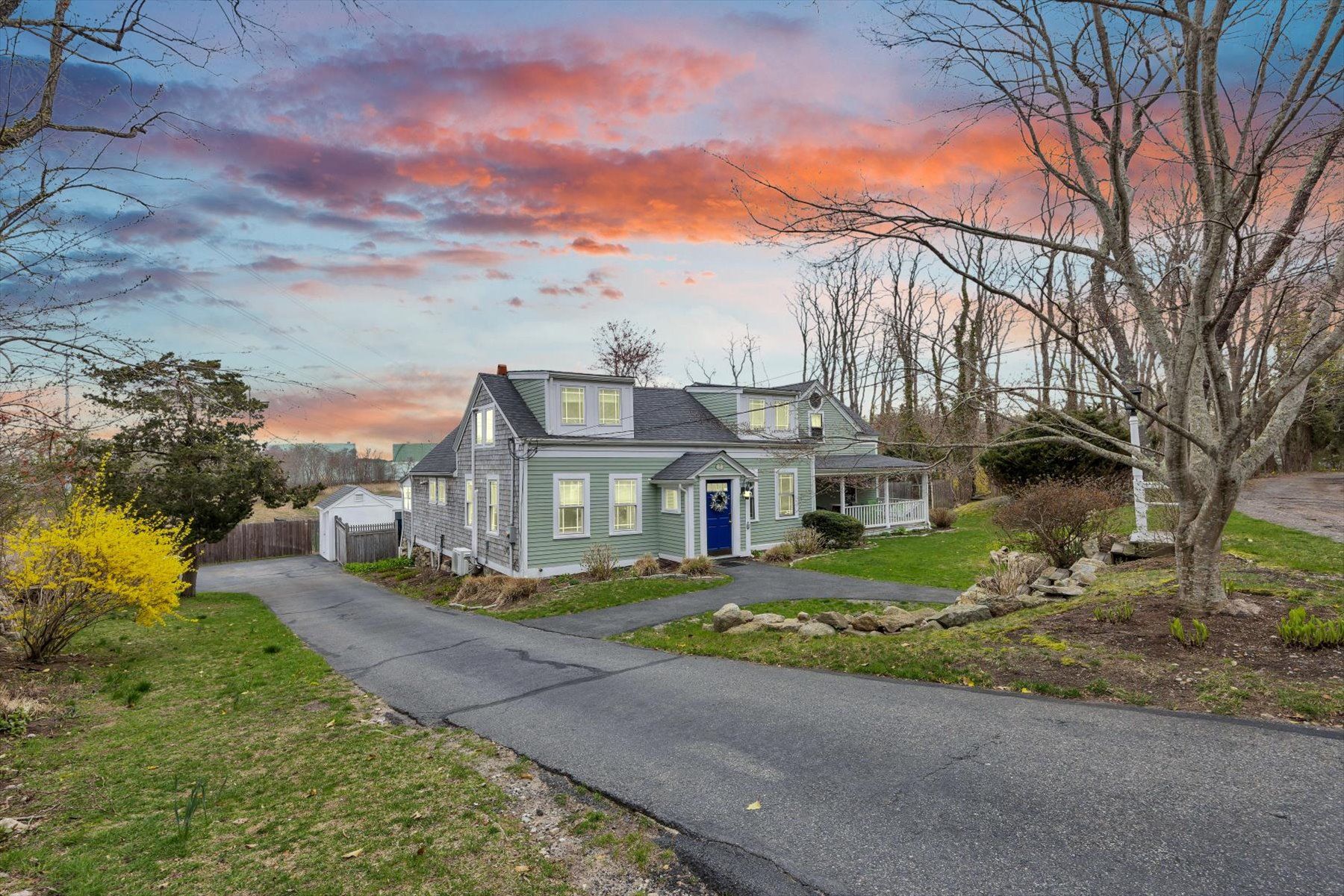 image Green exterior with a gravel driveway and lawn — your Cape Cod home for the stay