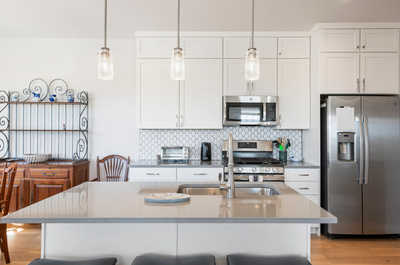 A sleek and modern kitchen boasts white cabinetry, complemented by a unique hexagonal tile backsplash and an inviting center island with seating options.