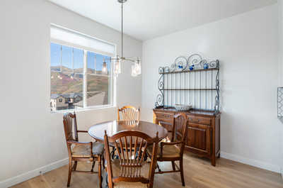 The dining area provides a perfect blend of traditional charm and contemporary design, featuring wooden furniture and an ornate shelving unit, all set against the backdrop of picturesque hillside views.