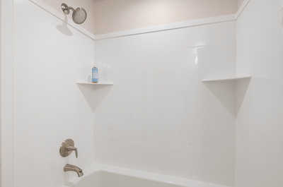 A minimalist bathroom shower with sleek fixtures, corner shelves, and a calming neutral color palette.