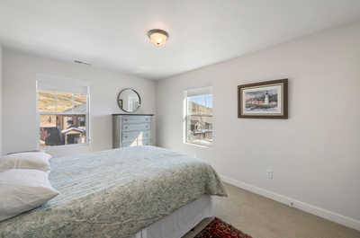 This queen bedroom features a harmonious blend of modern design and classic wooden furniture, bathed in natural light.