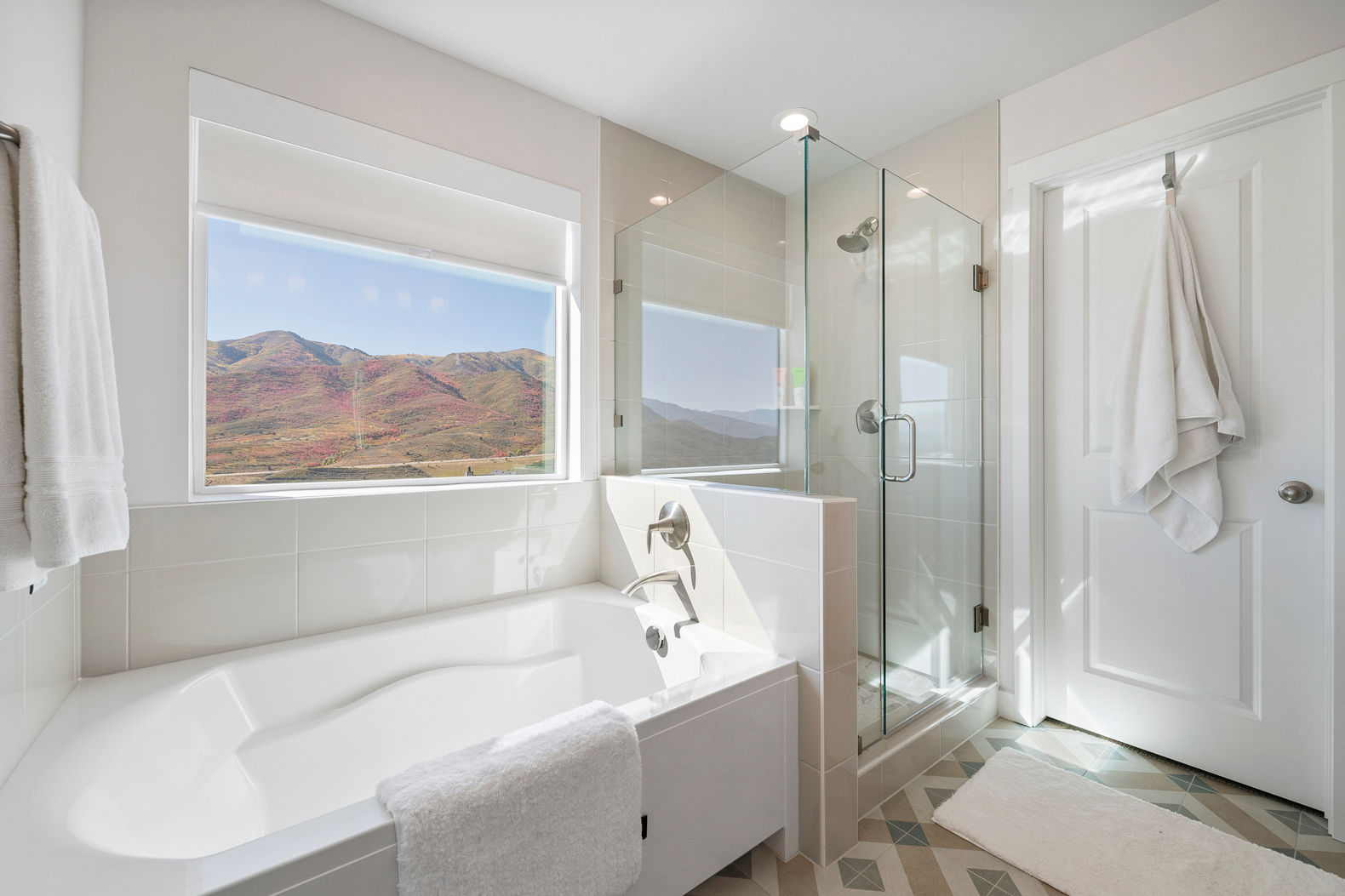 image A bright and airy master bathroom adorned with modern fixtures, geometric floor tiles, and a spacious mirrored vanity reflecting a picturesque mountain view