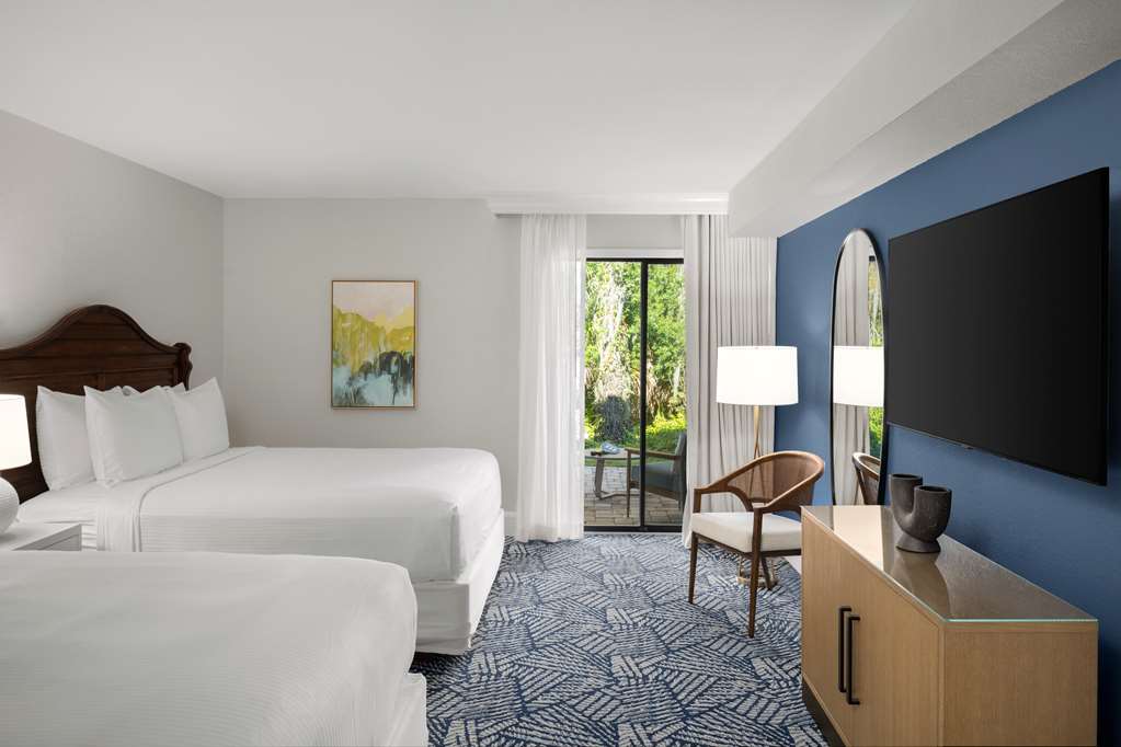 image Unwind in two plush queen beds for a restful stay in a bright, serene setting.