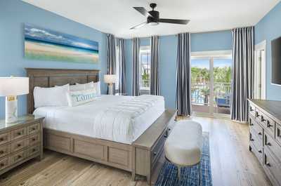Spacious master bedroom featuring ocean-inspired decor and a balcony with stunning views.