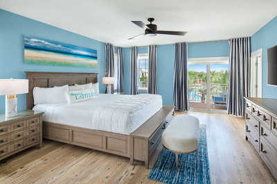 Spacious master bedroom featuring ocean-inspired decor and a balcony with stunning views.