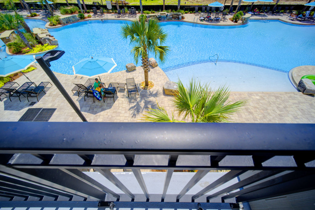 image Overlook the vibrant pool area from your private balcony, the perfect spot for evening relaxation.