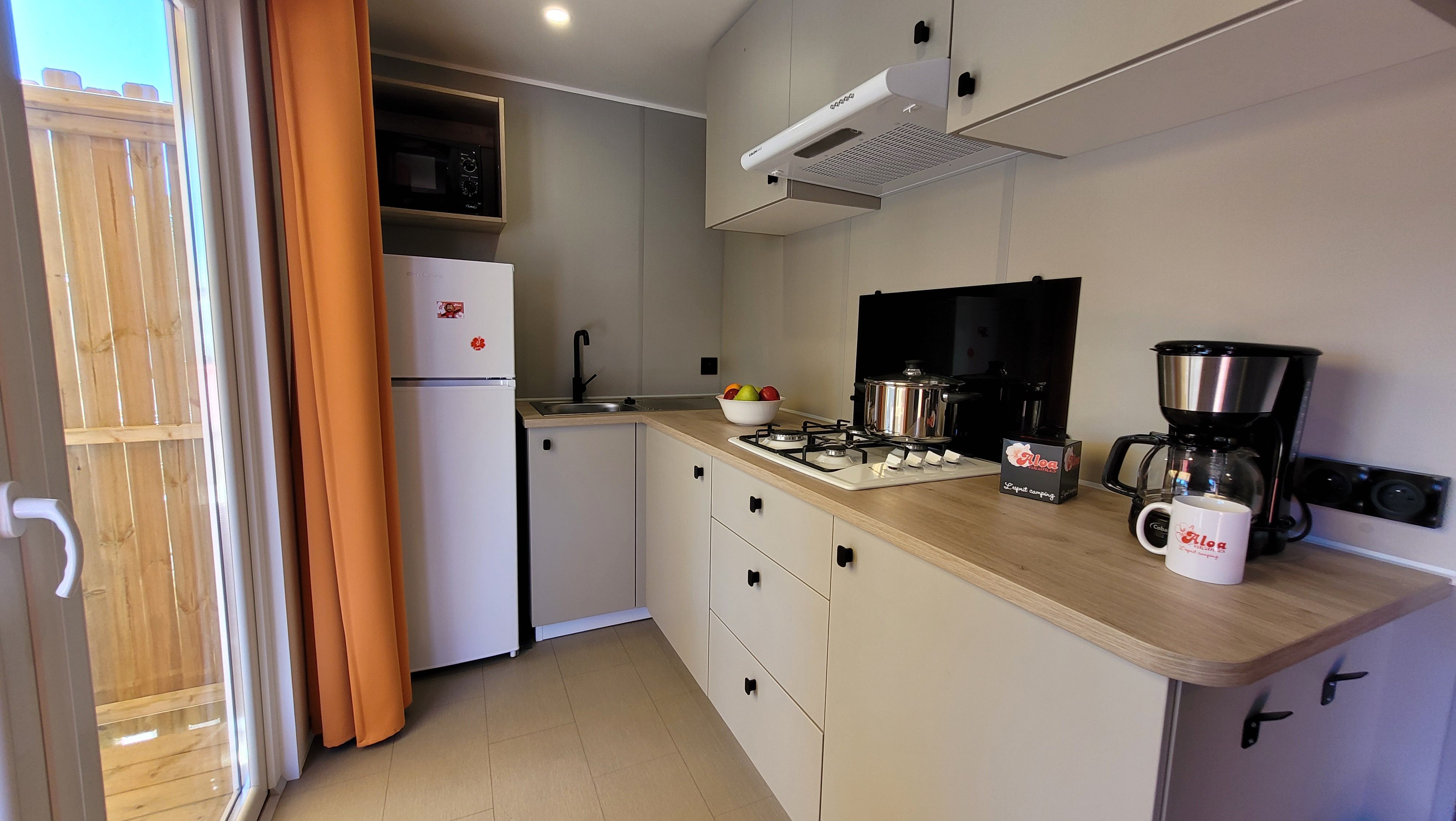 image The modern kitchen is equipped with essential appliances including a stove, refrigerator, and coffee maker, featuring a warm and inviting design.