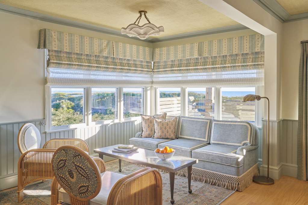 image Relax in a sun-drenched sitting room where wraparound windows invite in sweeping views and laid-back coastal charm.