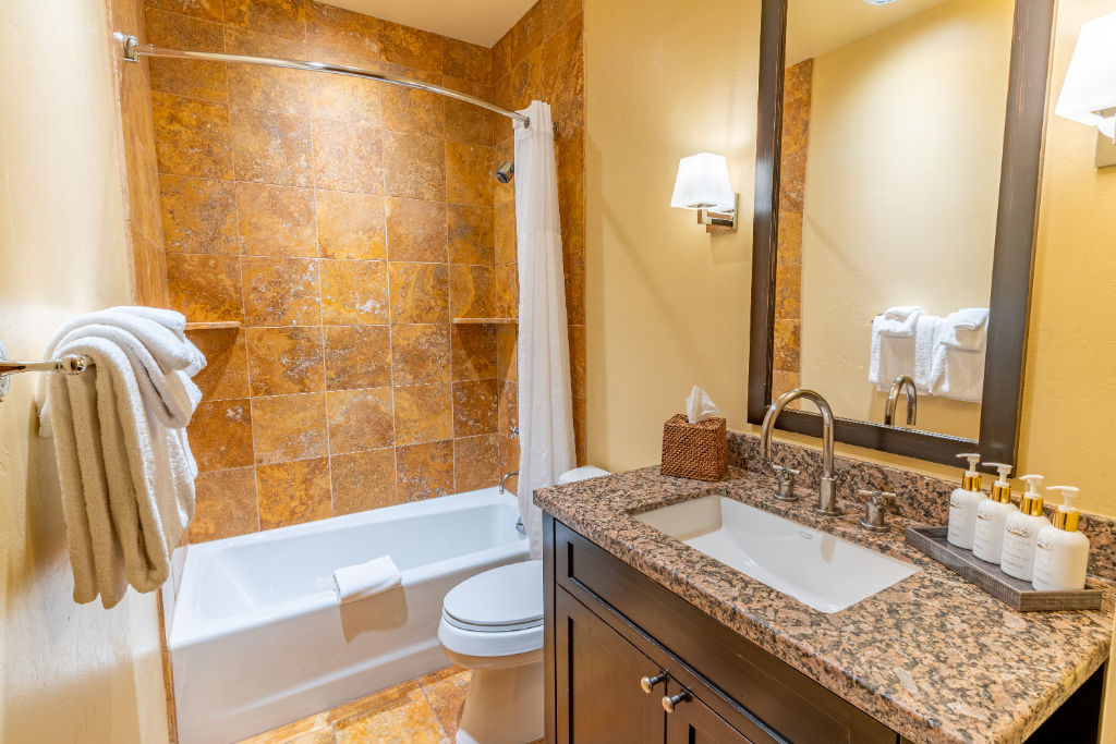 image Ensuite bathroom featuring natural stone tiles and soaking tub.