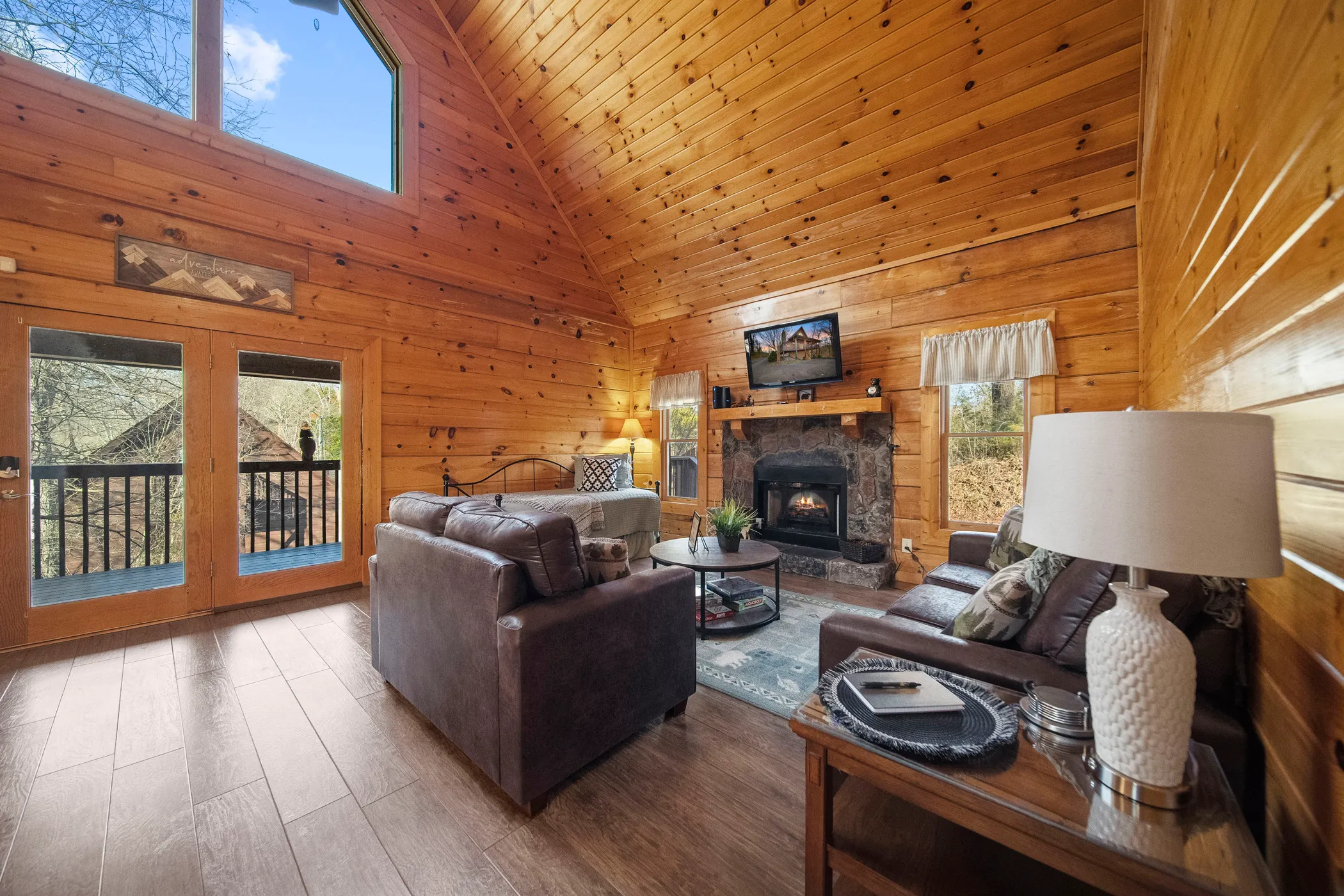 image Relax in the embrace of rustic charm with our cabin’s living area, featuring a cozy electric fireplace, smart TV with Roku, and comfortable leather sofas.