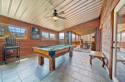 Challenge friends to a game of pool in this sunny room, complete with a charming bench, bar seating, and easy deck access through the impressive door.