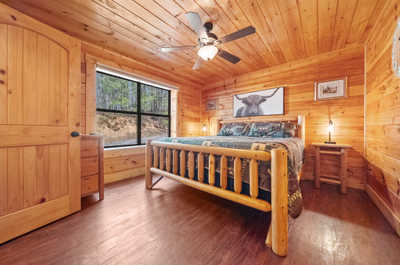 Restful slumber awaits in this king-sized haven, enveloped by the natural warmth of wood and serene views.