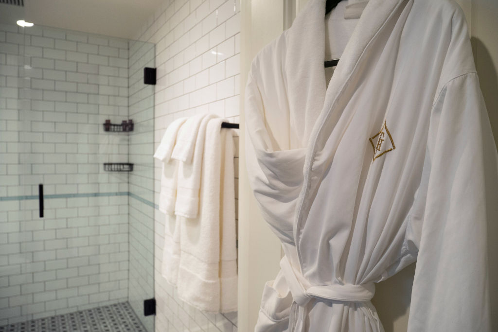 image Indulge in the simplicity and luxury of this bathroom, complete with plush robes and a spacious, glass-enclosed shower.