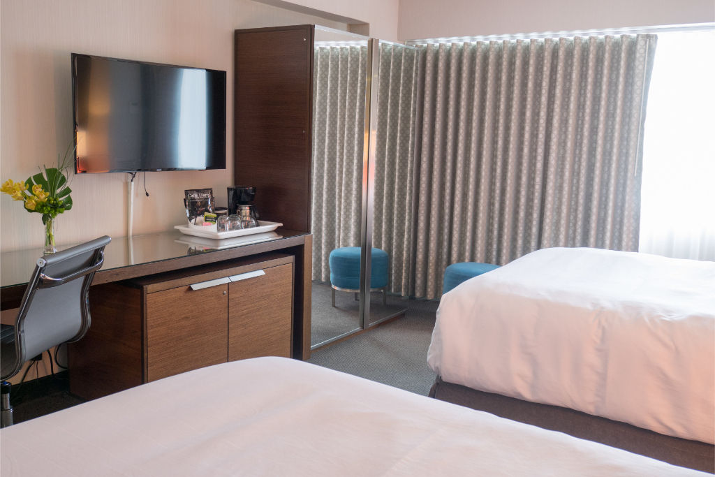 image Streamlined and welcoming room featuring two beds and a convenient workspace, perfectly suited for both leisure and business travelers.