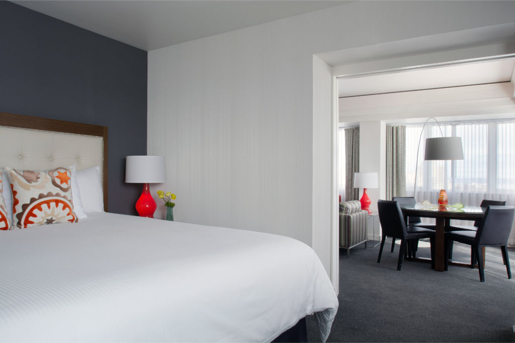 image Minimalist bedroom with crisp white bedding, vibrant accents, and a dining area.