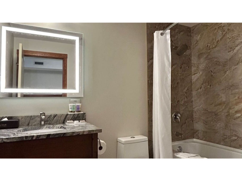 image Elegant bathroom with a well-lit vanity and a deep soaking tub, offering a relaxing retreat.