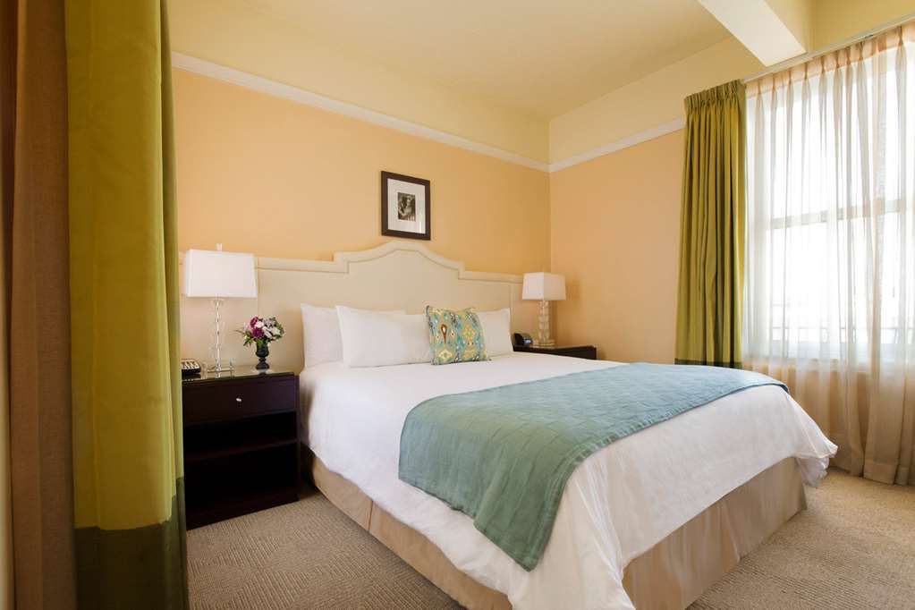 image Relax in our inviting room with a luxurious queen bed, tasteful decor, and ample natural light for a soothing ambiance.