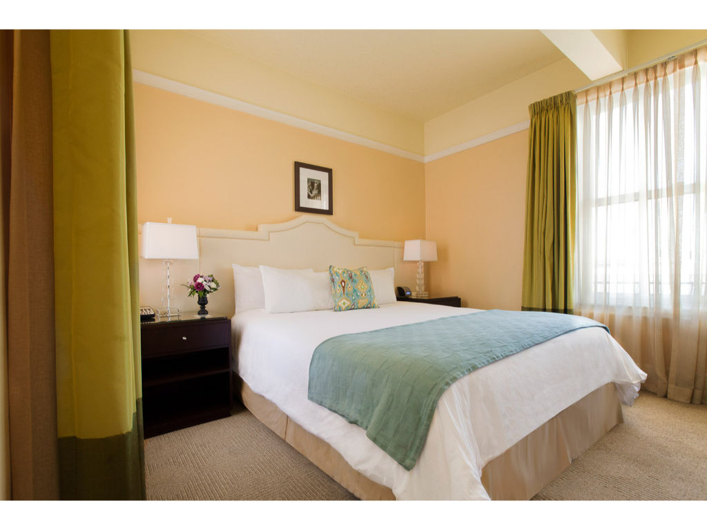 image Relax in our inviting room with a luxurious queen bed, tasteful decor, and ample natural light for a soothing ambiance.