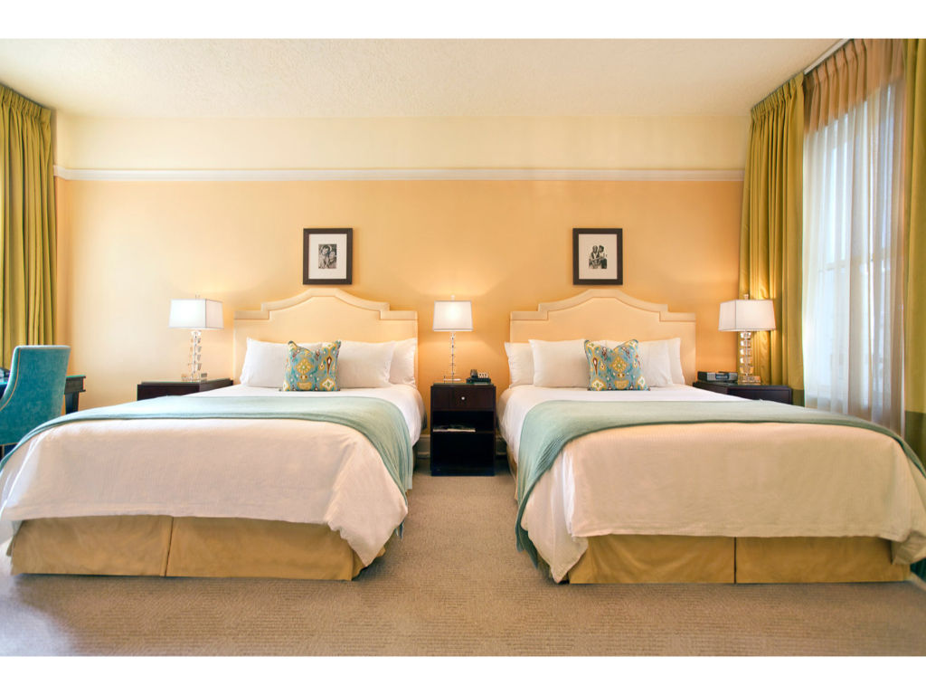 image Relax in our spacious room featuring two queen beds, contemporary decor, and ample natural light.