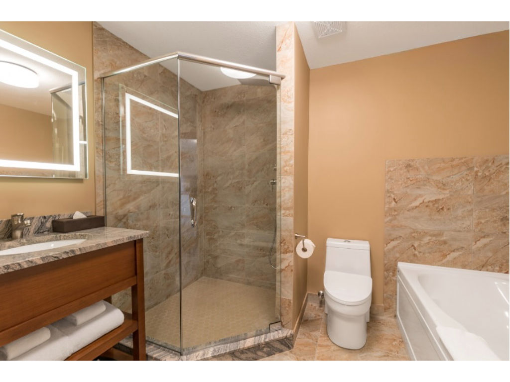 image Elegant bathroom with a glass-enclosed shower and deep soaking tub, designed for relaxation.