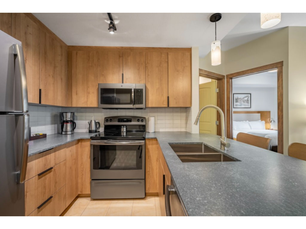 image Sleek and modern kitchen with warm wood tones and a spacious island, ideal for cooking and gathering.
