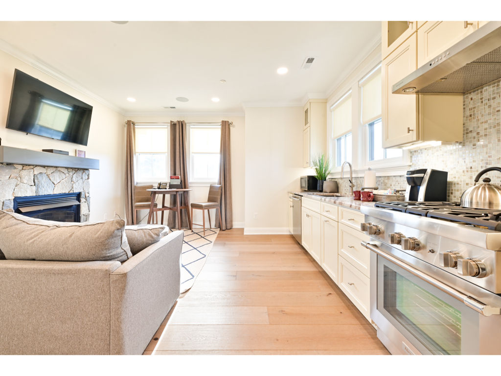 image Open-concept living area with a stylish kitchen, comfortable seating, and a fireplace, creating a welcoming and functional space.