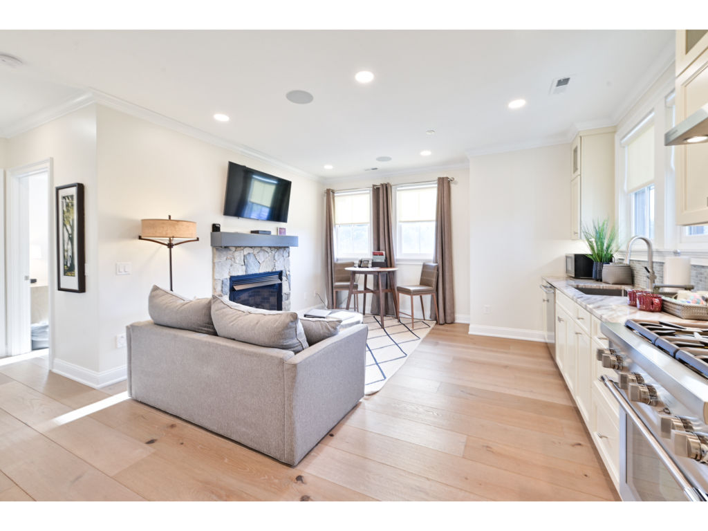 image Open-concept living area featuring a modern kitchen, comfortable seating, and a cozy fireplace, perfect for relaxing and entertaining.
