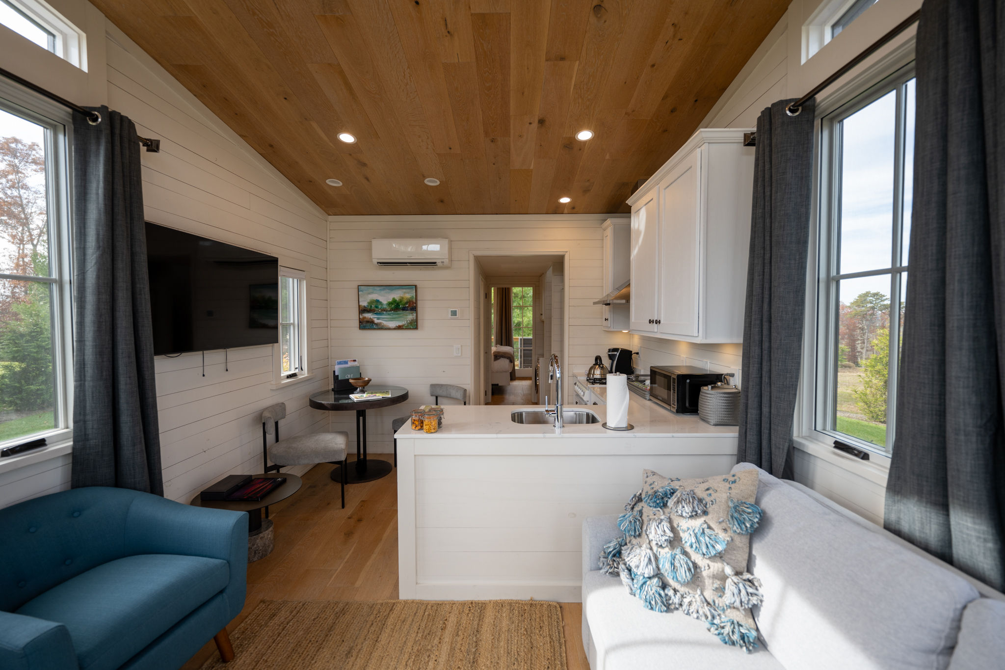 image Spacious open-plan living area with warm wood accents, large windows, and stylish furnishings.