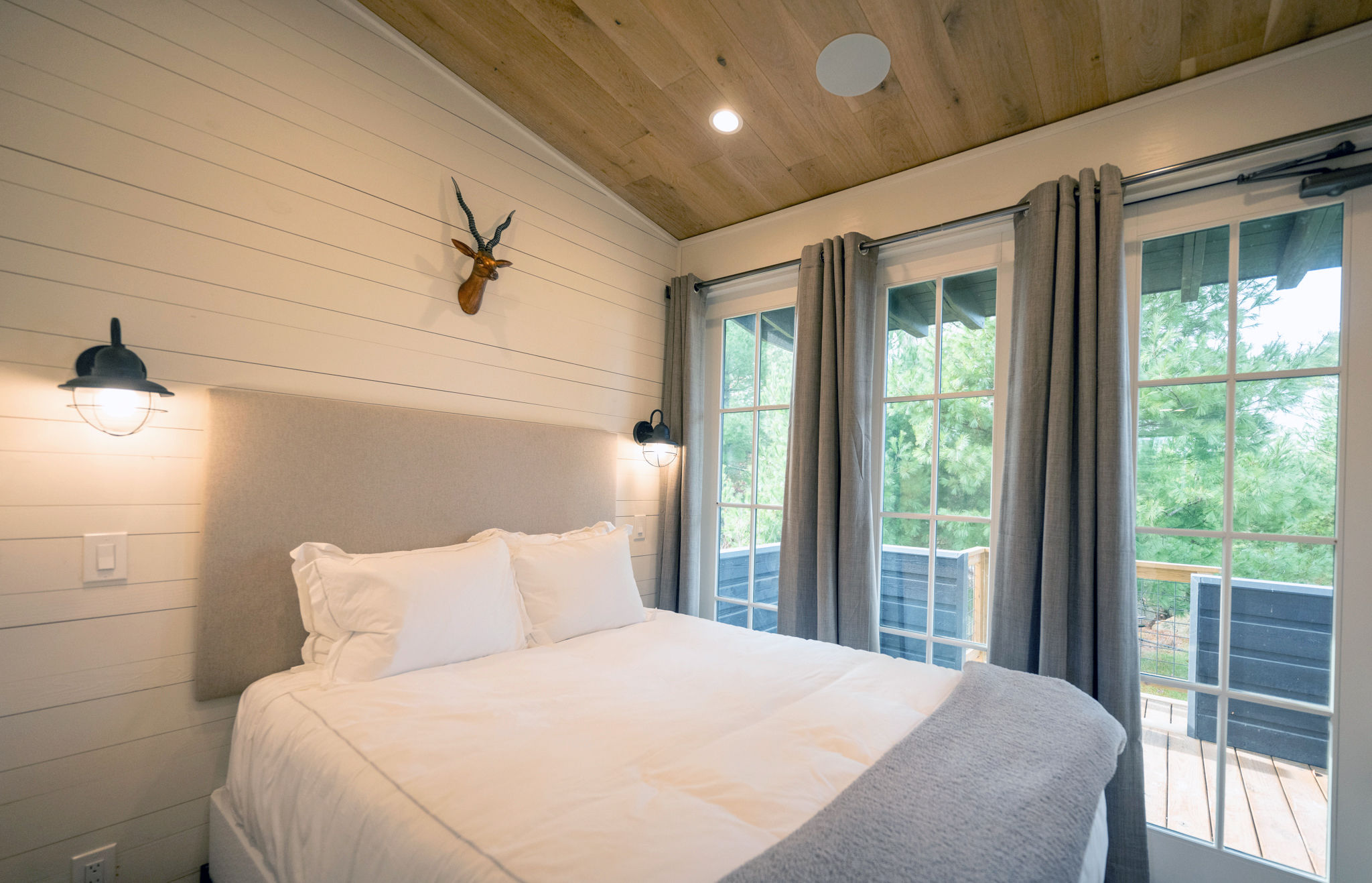image Rest comfortably in this bright and airy bedroom, featuring large windows and modern decor for a peaceful night’s sleep.