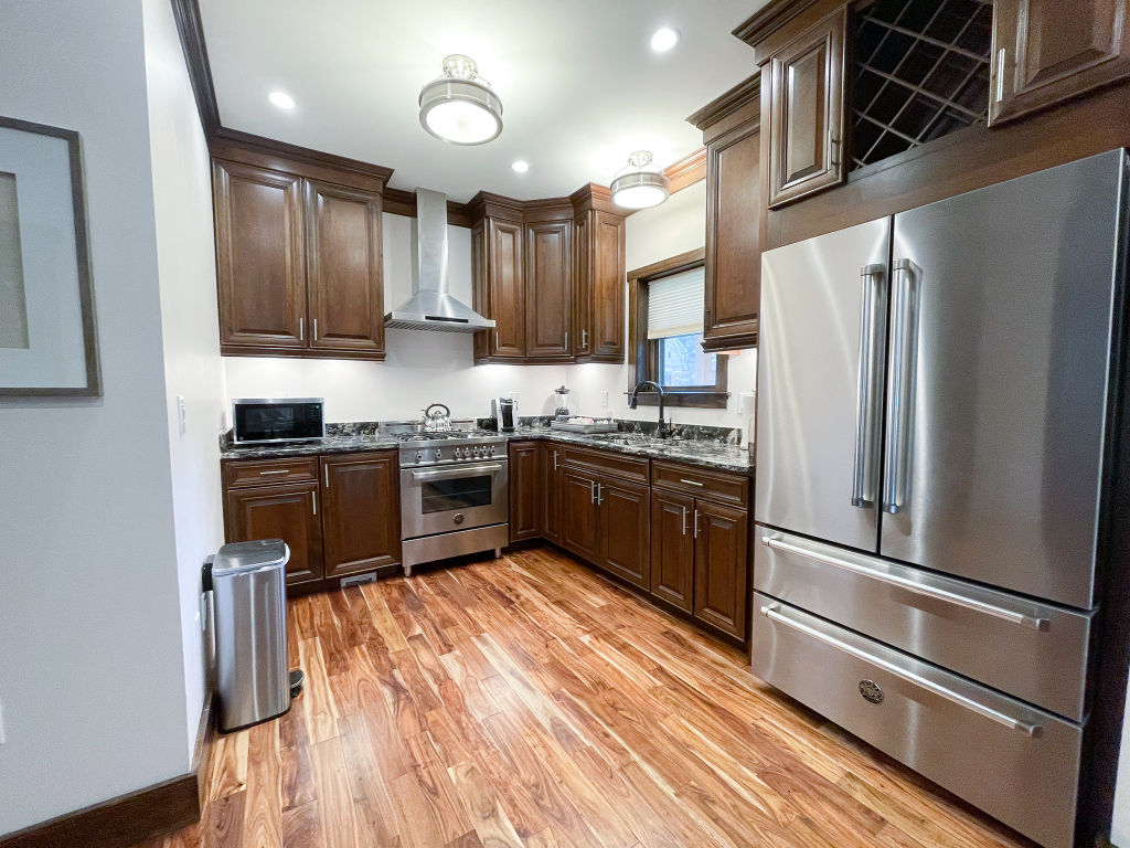 image Fully equipped kitchen with stainless steel appliances and wooden cabinetry.