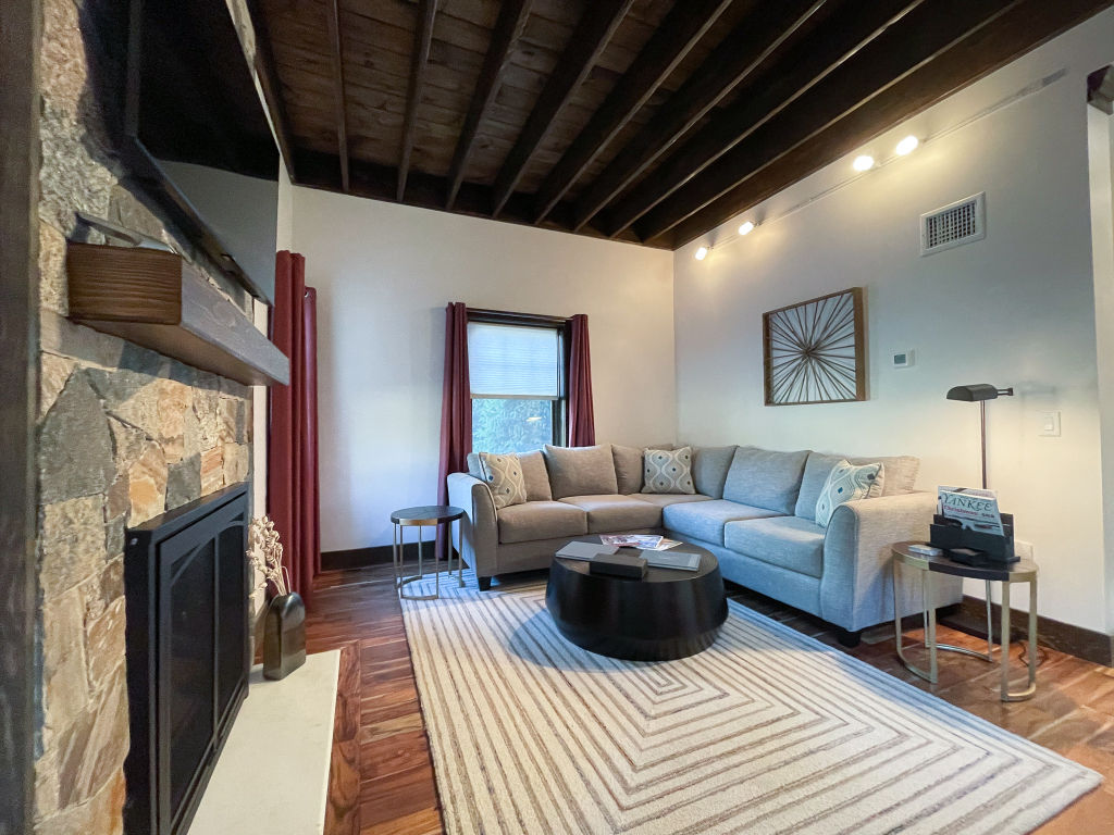 image Inviting living area featuring a stone fireplace and modern decor.