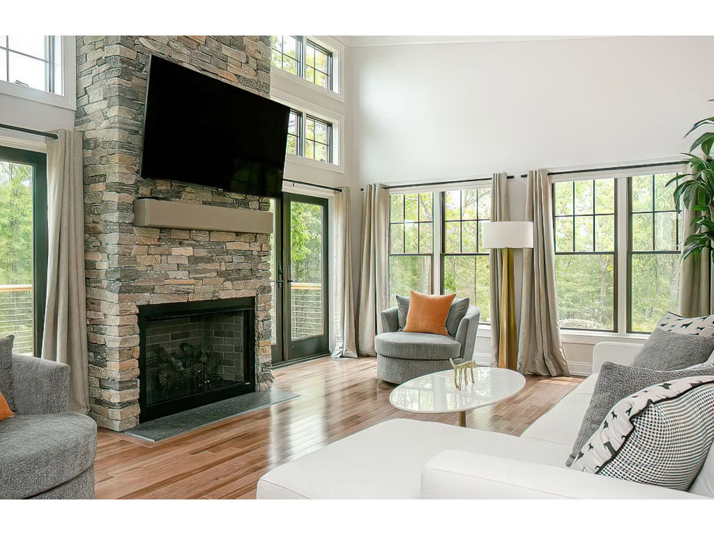 image Elegant living room with a stone fireplace, modern decor, and expansive windows that bring the beauty of the outdoors inside.
