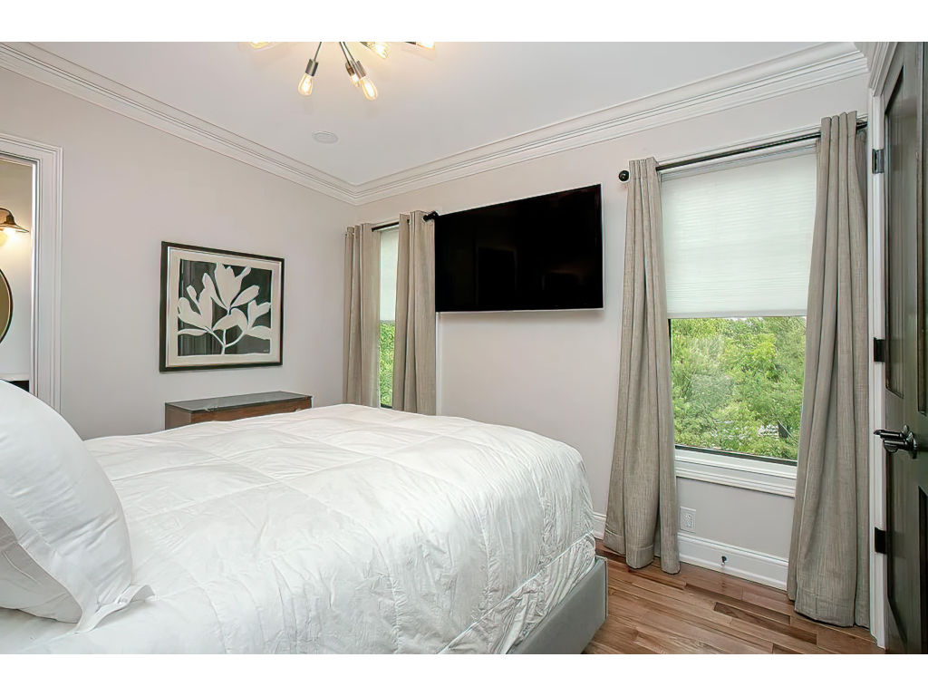 image Cozy bedroom featuring a plush bed, modern decor, and large windows offering serene views of the surrounding landscape.