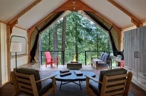 image Spacious glamping tent with a comfortable seating area, offering scenic forest views.