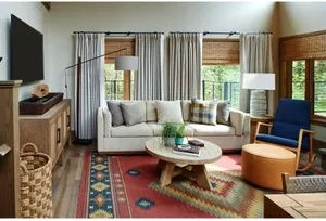 image Inviting living room with comfortable seating and large windows overlooking the greenery.