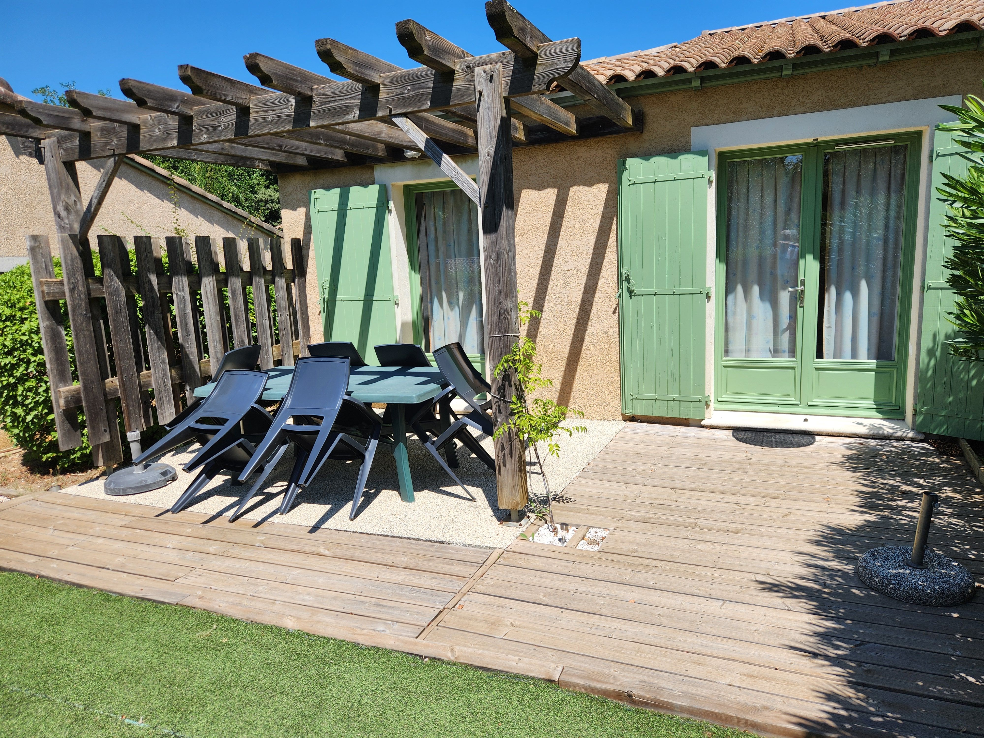 image Take a seat at the terrace table under the pergola, surrounded by garden greenery.