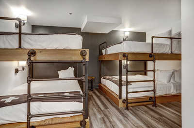 Modern bunk room with rustic-industrial design, offering a cozy and stylish retreat for group stays.
