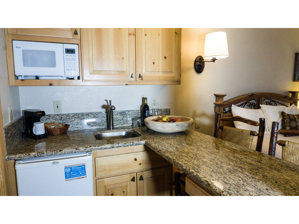 image Prepare meals with ease in this kitchen, featuring granite countertops, a microwave, and all the essentials.