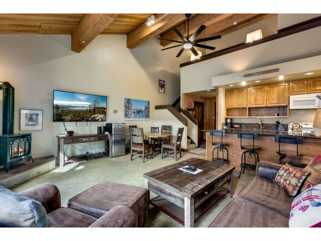 image Enjoy the open-plan living room, showcasing rustic wooden beams, ample seating, and a flat-screen TV.