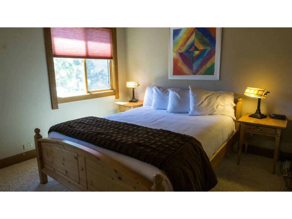 image Bright and inviting bedroom featuring a comfortable bed, bedside lamps, and charming artwork.