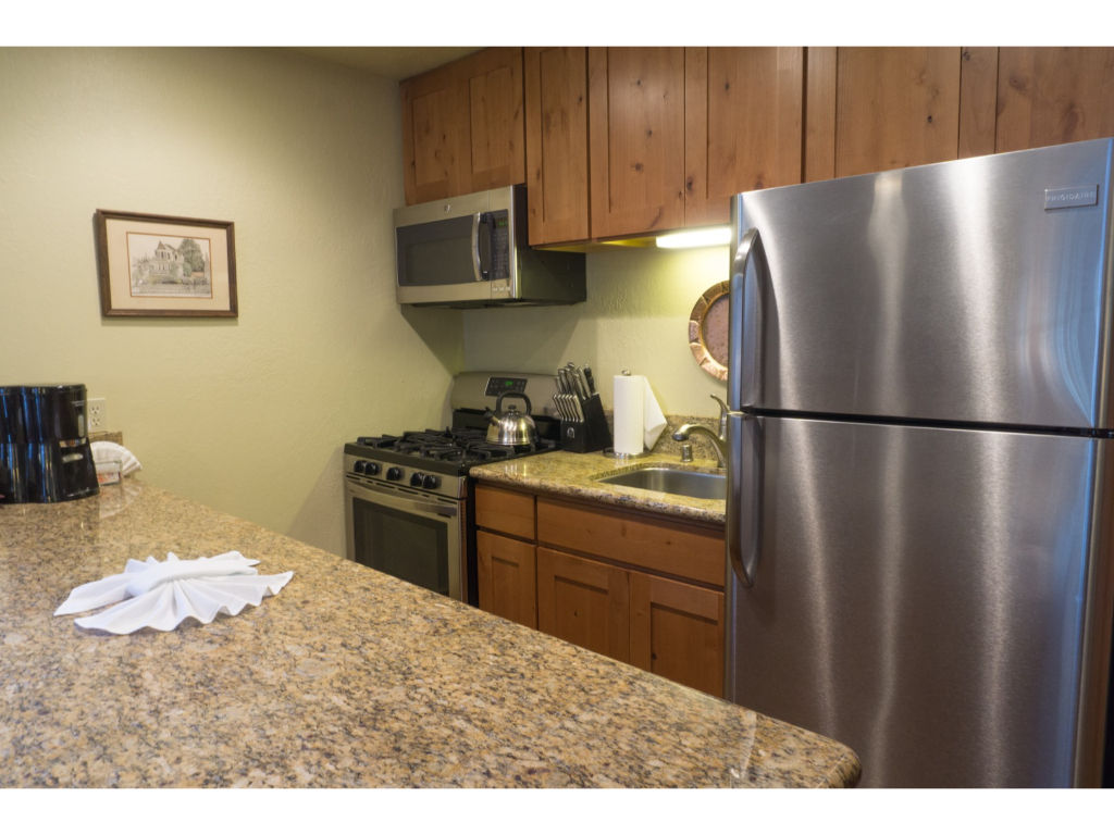 image Modern kitchen equipped with stainless steel appliances, granite countertops, and wooden cabinets.