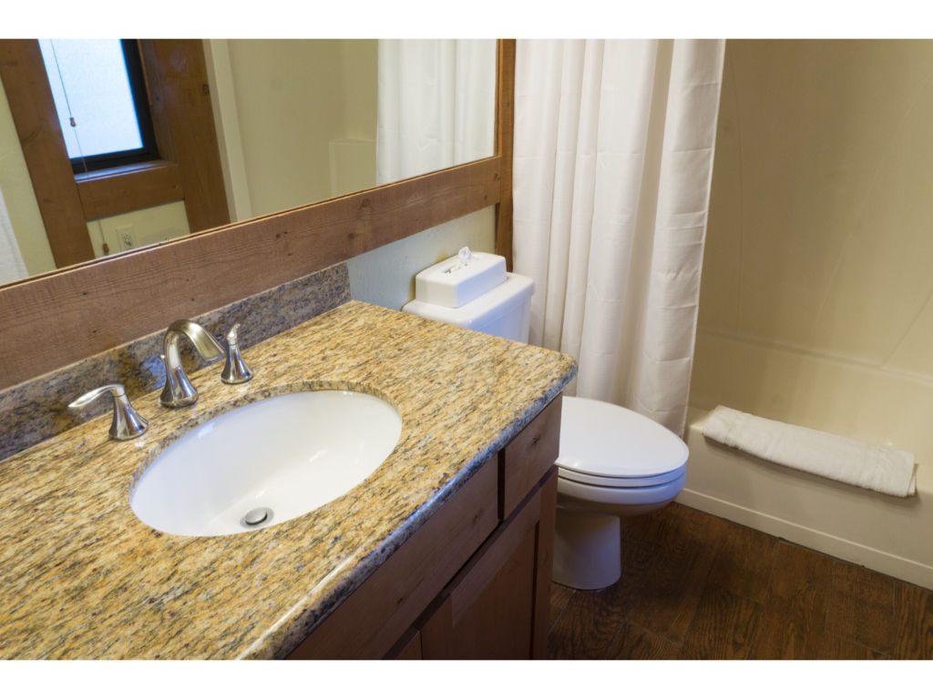 image Bright bathroom featuring a large vanity with ample counter space and a well-lit mirror.
