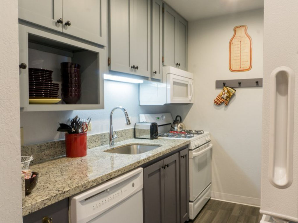 image Prepare meals effortlessly in this compact kitchen equipped with modern amenities and granite countertops.