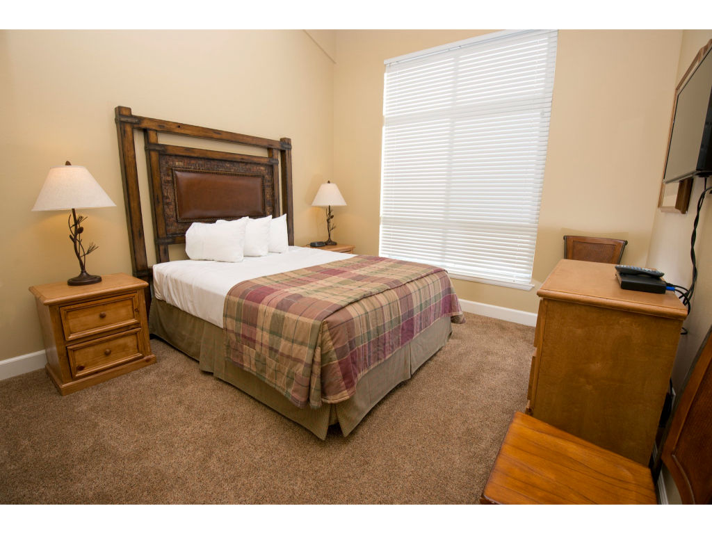 image This bright bedroom features a comfortable queen bed, stylish rustic decor, and large windows letting in plenty of natural light.