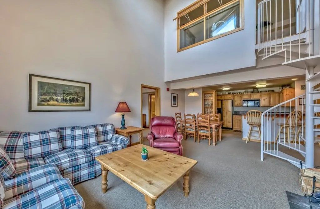 image Relax in the expansive living room with high ceilings, cozy seating, and a loft area, perfect for additional sleeping space or a quiet retreat.