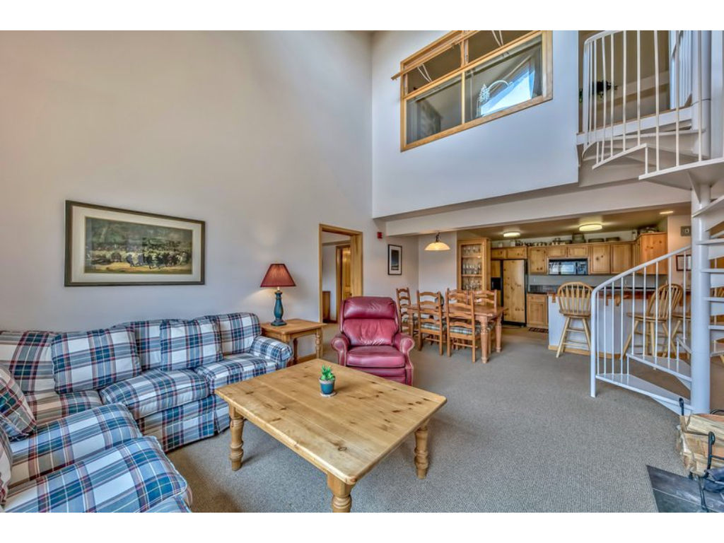 image Relax in the expansive living room with high ceilings, cozy seating, and a loft area, perfect for additional sleeping space or a quiet retreat.