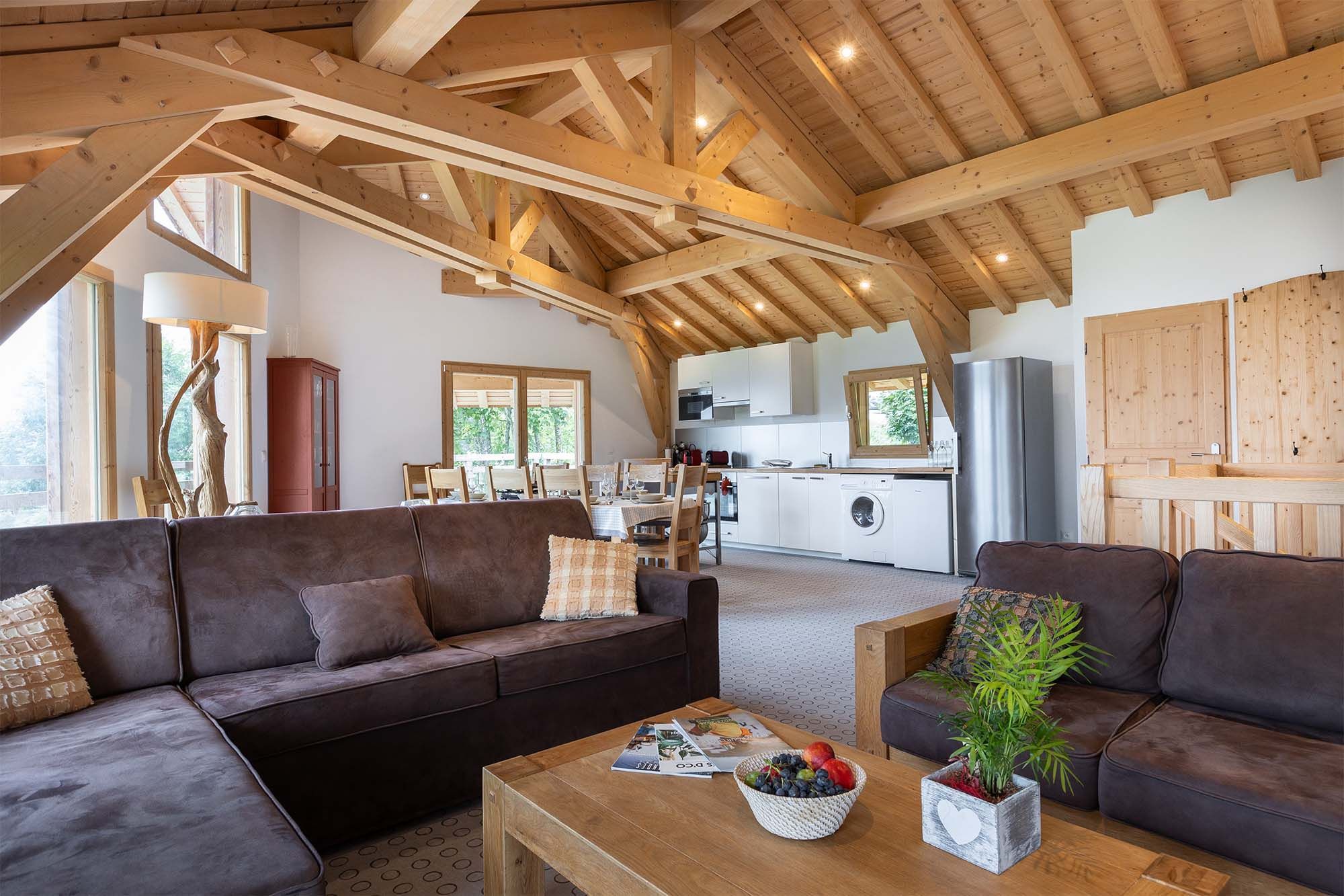 image Relax in the inviting living room with its comfortable seating, high wooden ceilings, and large windows that fill the space with natural light. Ideal for movie nights or simply lounging after a day of adventure.