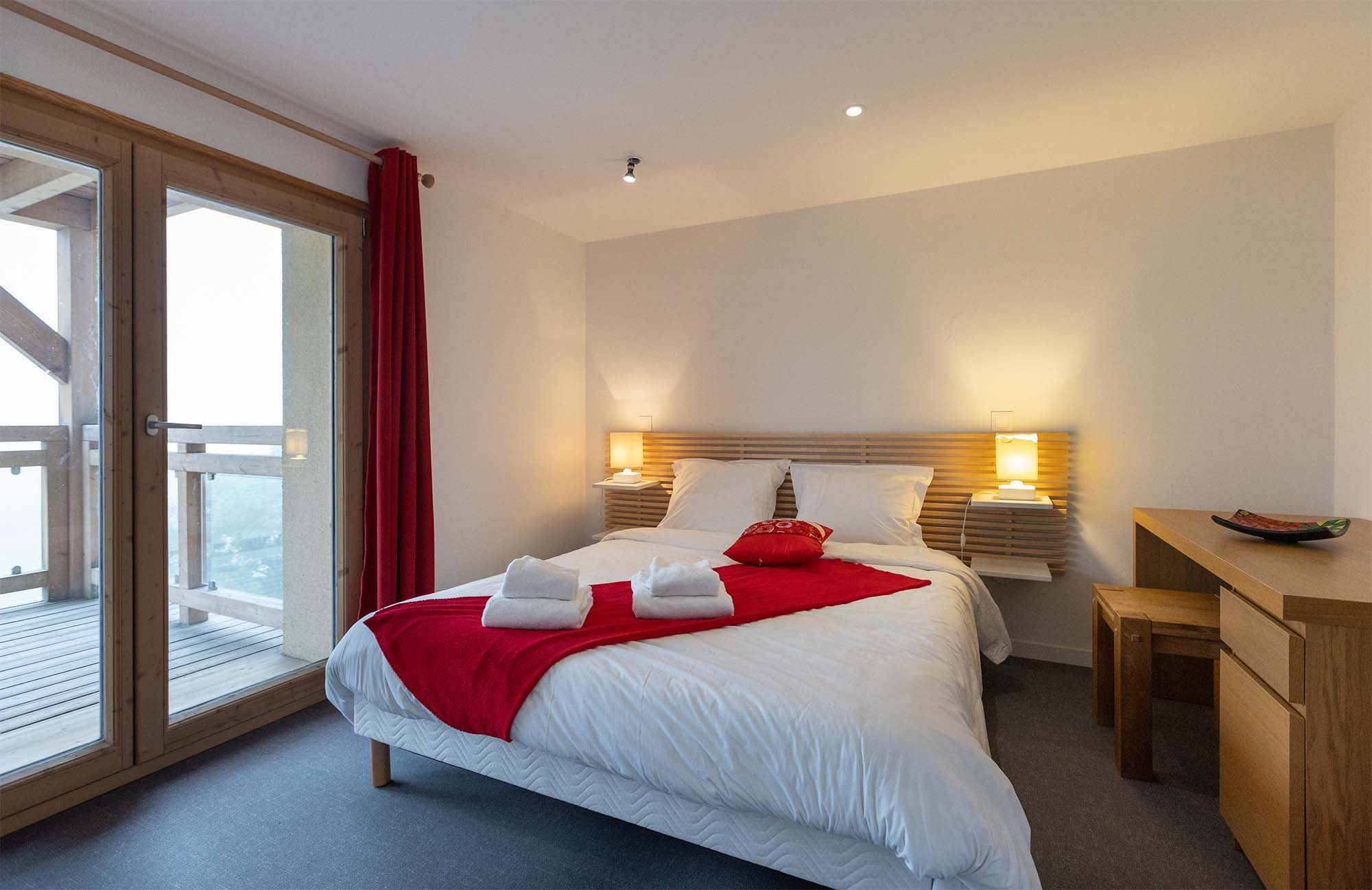 image Drift into restful sleep in this bright and cozy bedroom featuring a soft double bed and direct access to a private balcony, perfect for enjoying the fresh mountain air.