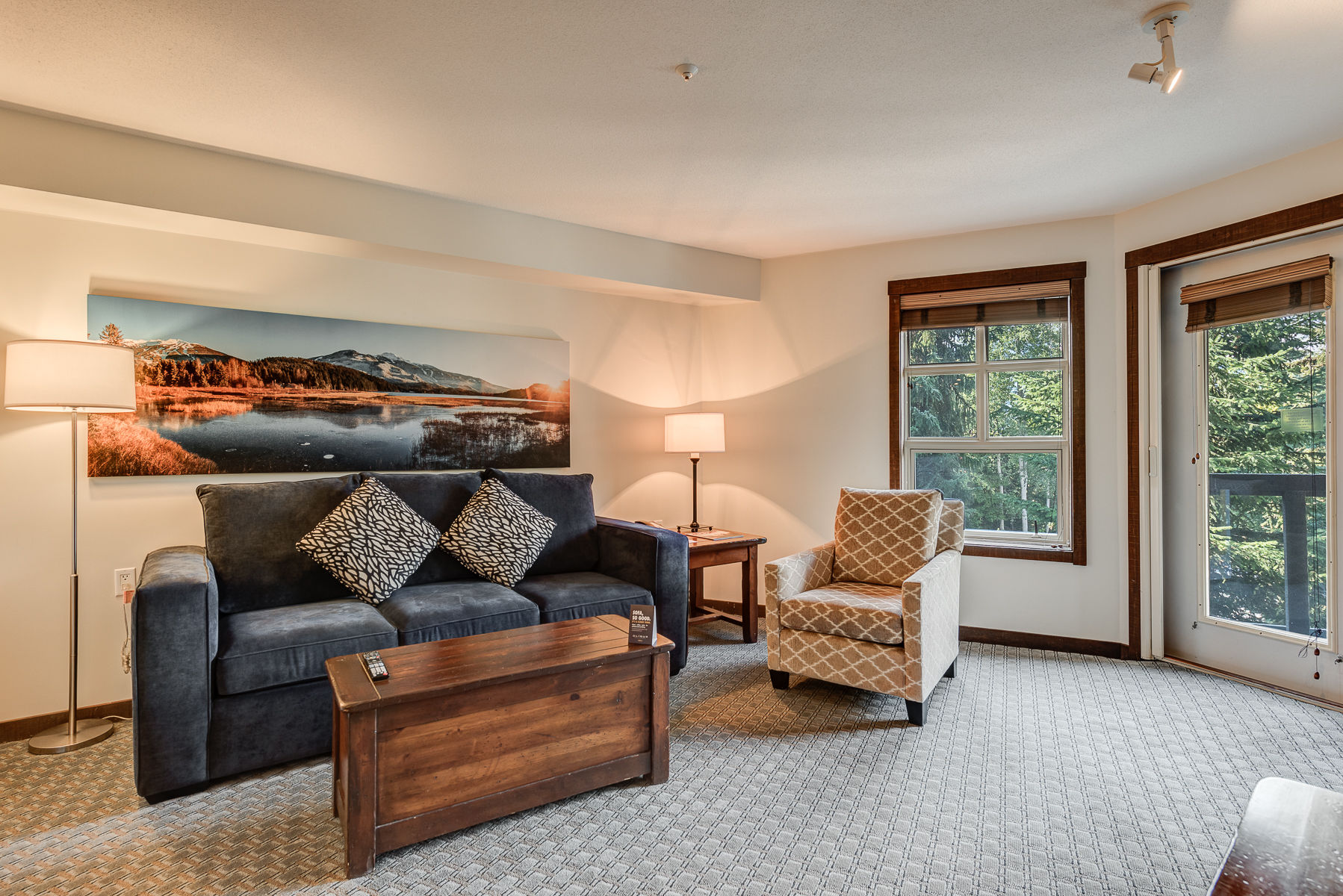 image Cozy living room with plush seating and large windows offering nature views.