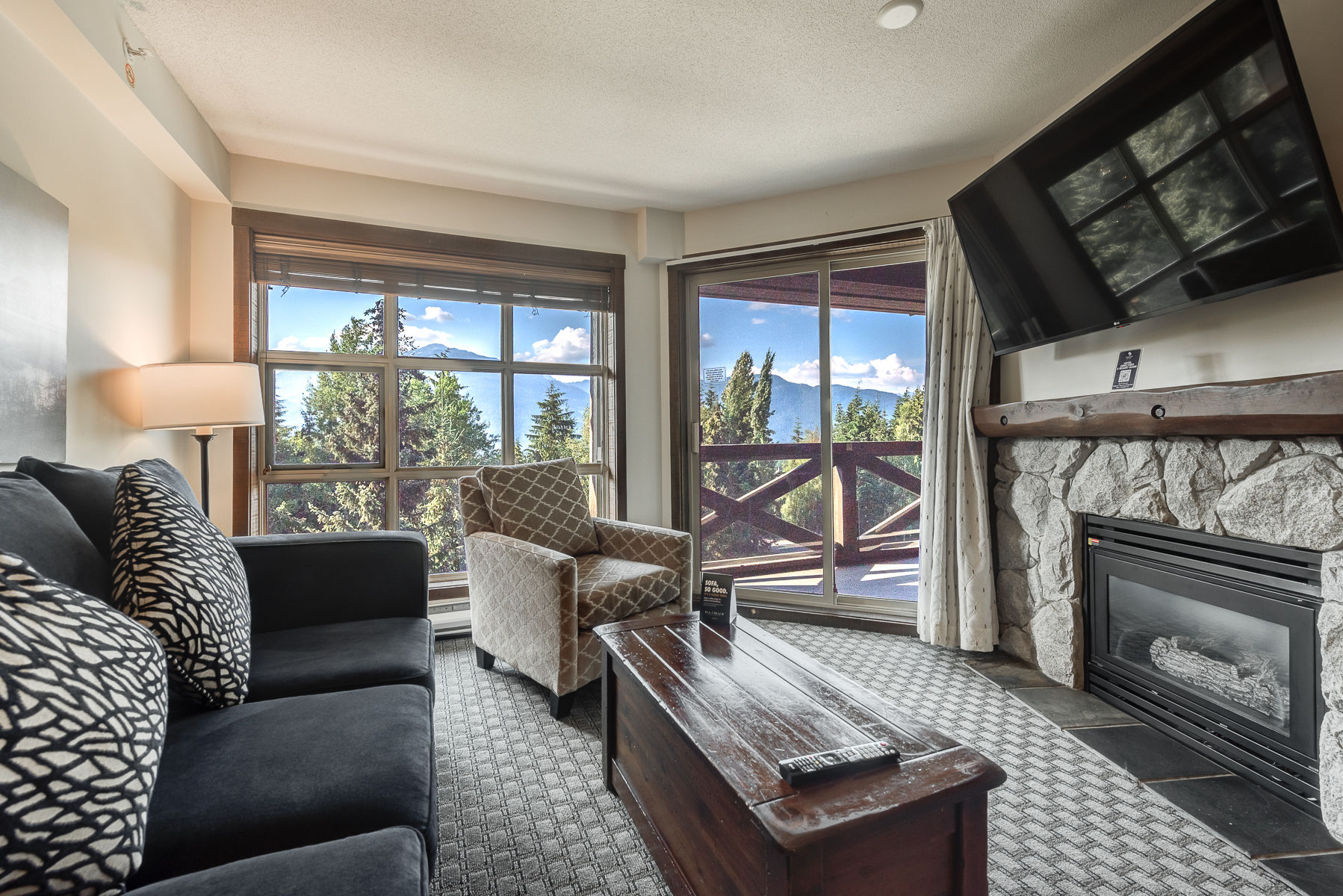 image Cozy living room with a stone fireplace and large windows with scenic views.